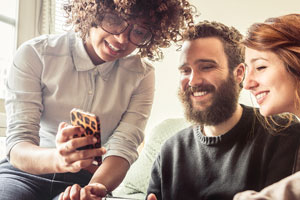 Three young adults looking at a phone